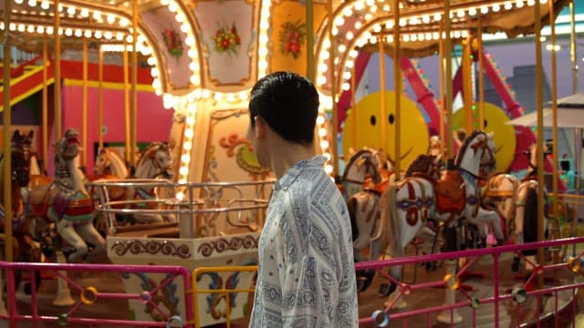 Man standing near a carousel at night