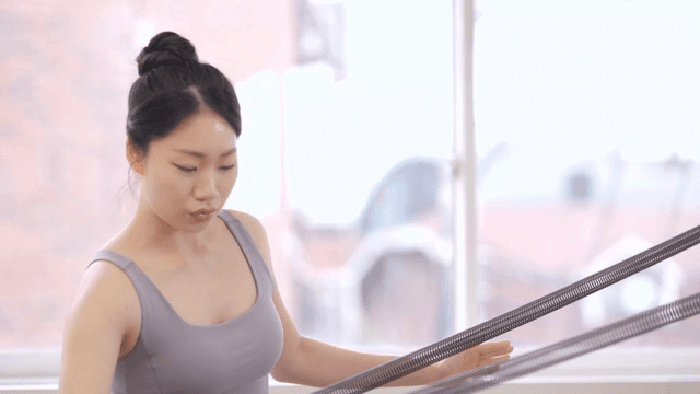 Pilates instructor assists a student indoors