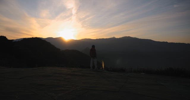 산에서 일출을 바라보는 사색적인 사람