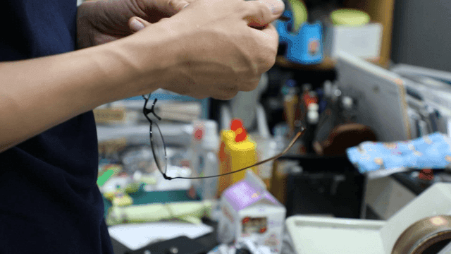 Person adjusting glasses in a cluttered room