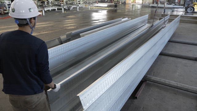 Worker handling metal beams in a factory