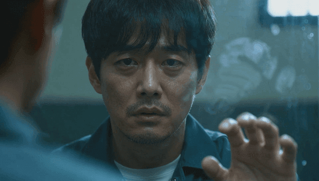 면회실 칸막이에 정면을 보며 손을 대는 슬픈 남성 죄수