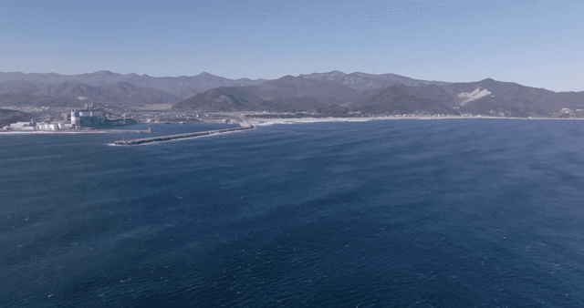 산과 건물이 보이는 해안 풍경