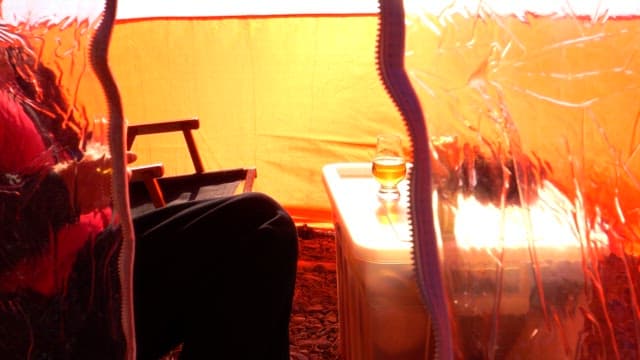 People relaxing and drinking beer inside a tent on a sunny day