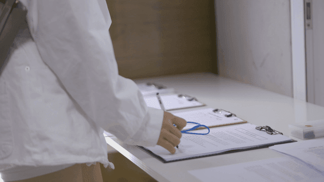 Person filling out forms on a clipboard