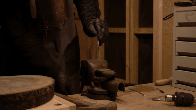 금속 막대를 망치로 구부리는 공예가