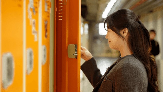 Female college student opening locker in hallway