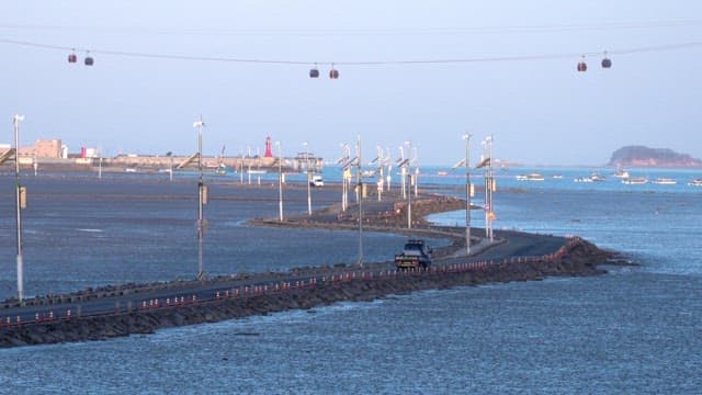 Coastal road and cable car at dusk on the mudflats exposed by low tide