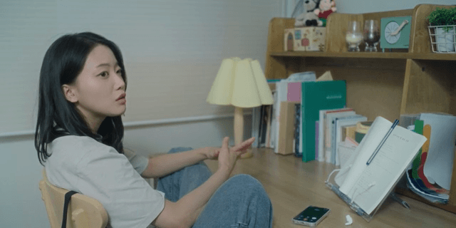 방에서 책상에 앉아 누군가와 대화하는 여성