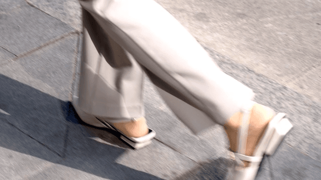 Legs of office worker walking on sidewalk