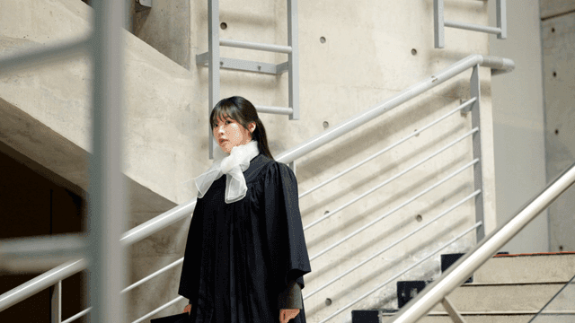 Graduates coming down stairs in graduation gowns