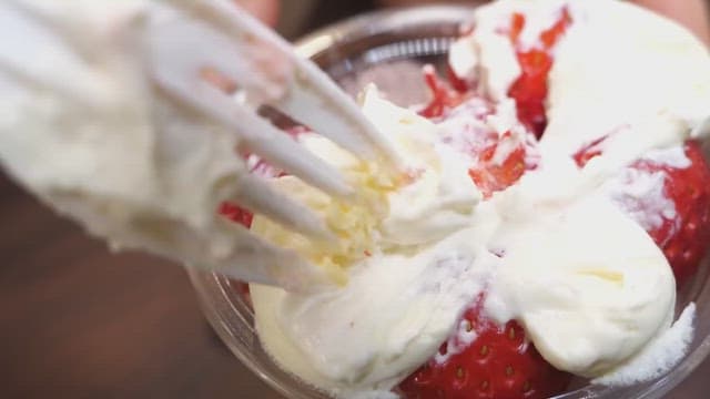 Close-up of a spoon dipping into a creamy strawberry dessert