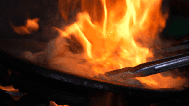 Grilled large intestine on hot grill with flames rising