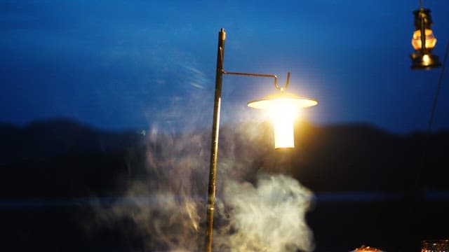 연기가 피어오르는 어두운 밤을 밝히는 캠핑용 랜턴
