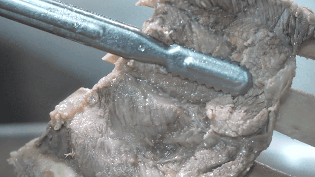 Tongs lifting tender beef ribs