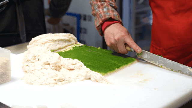 Person cooking green and white fish cake batter