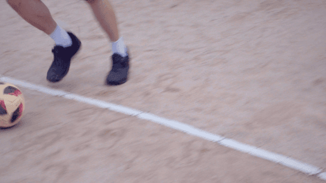 모래 운동장에서 축구를 하는 사람