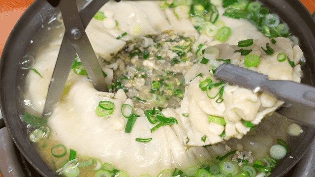 Scissors for cutting dumpling soup boiling in pot