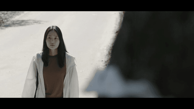 길 위에 서서 무언가를 바라보는 여성