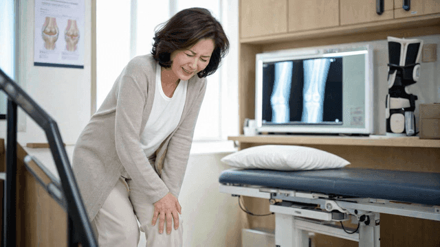 Elderly woman holding her knee at clinic