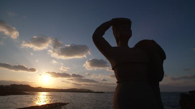 Sunset view at the seaside with a silhouette of a statue