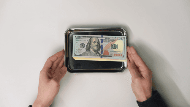 Hand offering a tray with dollar