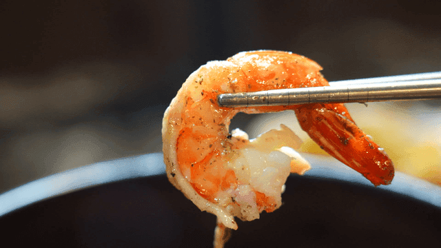 Cooked gambas shrimp picked up with chopsticks