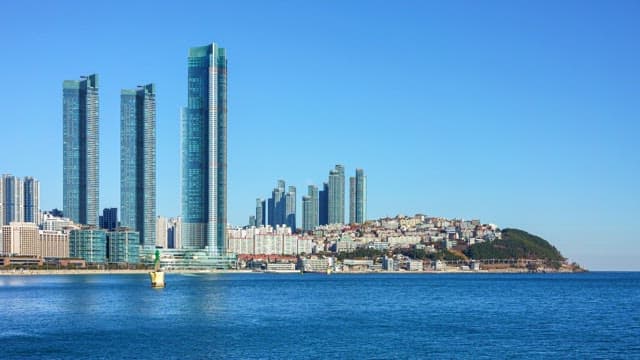 화창한 낮부터 밤까지 부산의 고층 건물과 동백섬 풍경