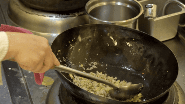 Chef cooking fried rice with vegetables in wok