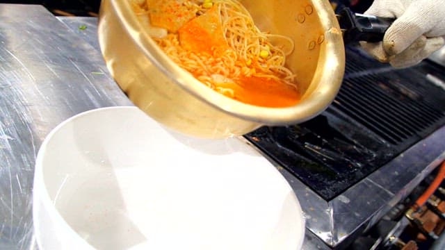 Pouring ramyeon with bean sprouts into a bowl