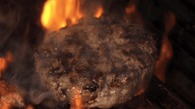 Beef burger patty in rising flames