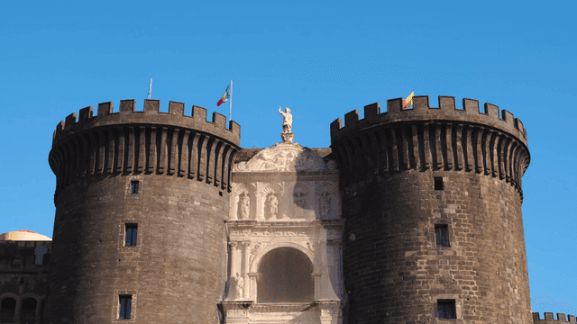 Historic castle with flags under clear sky