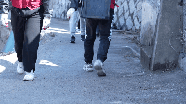 People carrying briquettes on their backs through narrow alleyways