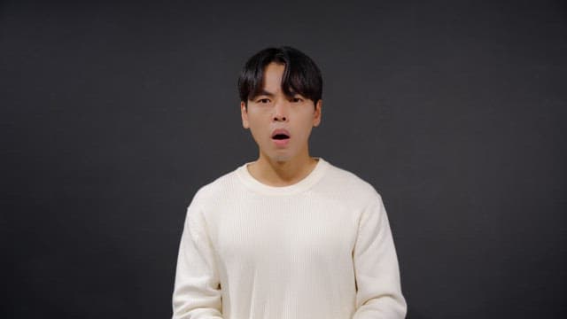 Man in white sweater with mouth open in surprise