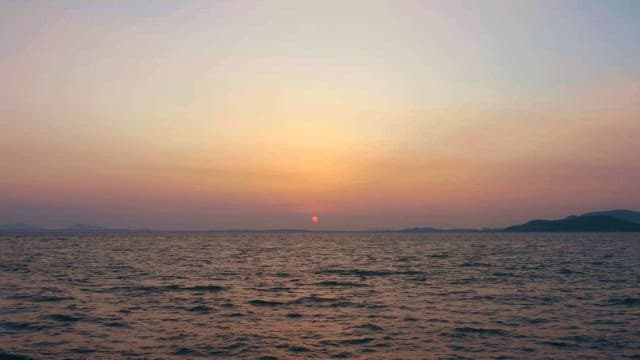 먼 산이 있는 평화로운 바다 일몰