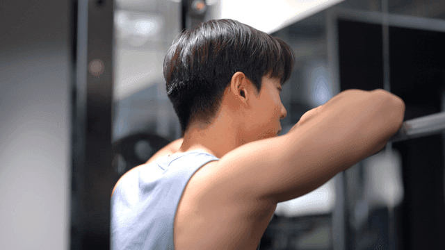 헬스장에서 운동 중 바벨에 기대어 휴식하는 남성