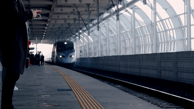 Train approaching platform in front of office worker