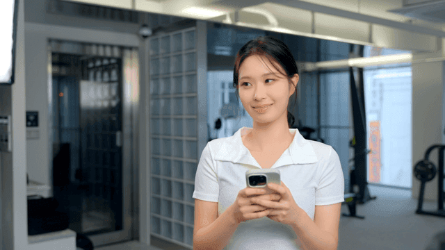 헬스장에서 스마트폰을 들고 미소 짓는 여성