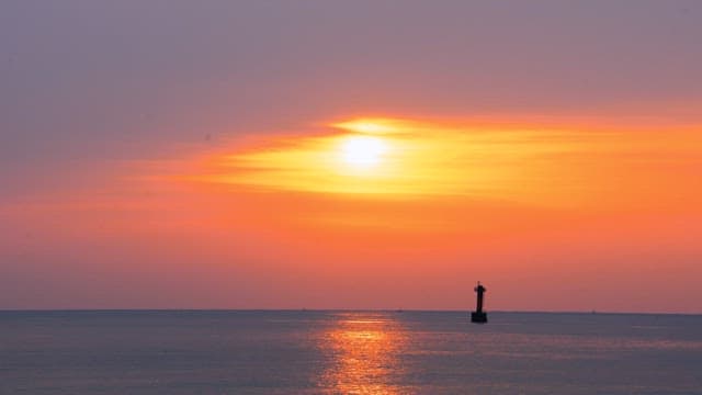 Helicopter flying over the calm and peaceful sea at sunset