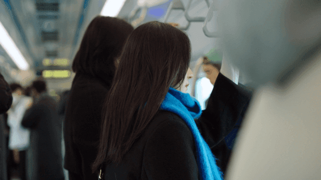 혼잡한 기차 안에 서 있는 여성의 옆모습