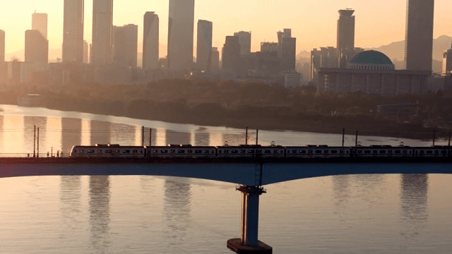 Train crossing a bridge with city skyline