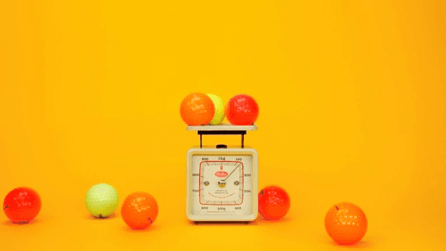노란색 배경에 저울 위의 컬러 골프공들