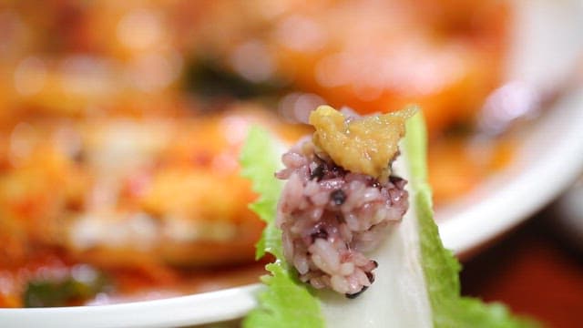 Korean dish with rice and spicy braised fish on lettuce