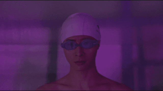Swimmer preparing with goggles in purple light