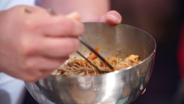 Mixing seasoning sauce with cold noodles