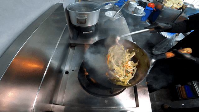 Chef stir-frying vegetables in hot wok