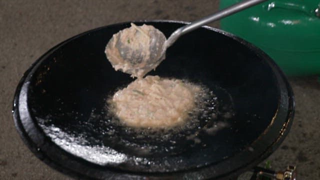 기름을 두른 뜨거운 팬 위에서 지글거리는 부침개 반죽