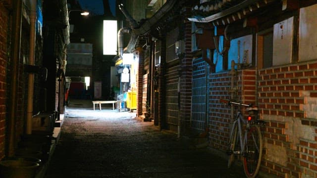 Narrow alleyway at night with a bike leaning against a brick wall