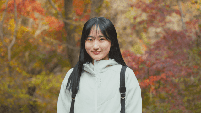 알록달록한 가을 숲에 서 있는 젊은 여성