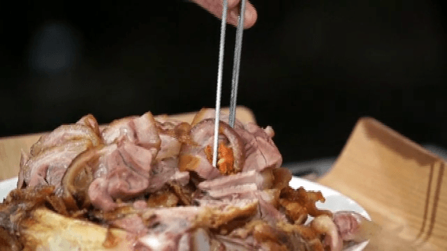 Picking up braised pig's feet on a plate with chopsticks